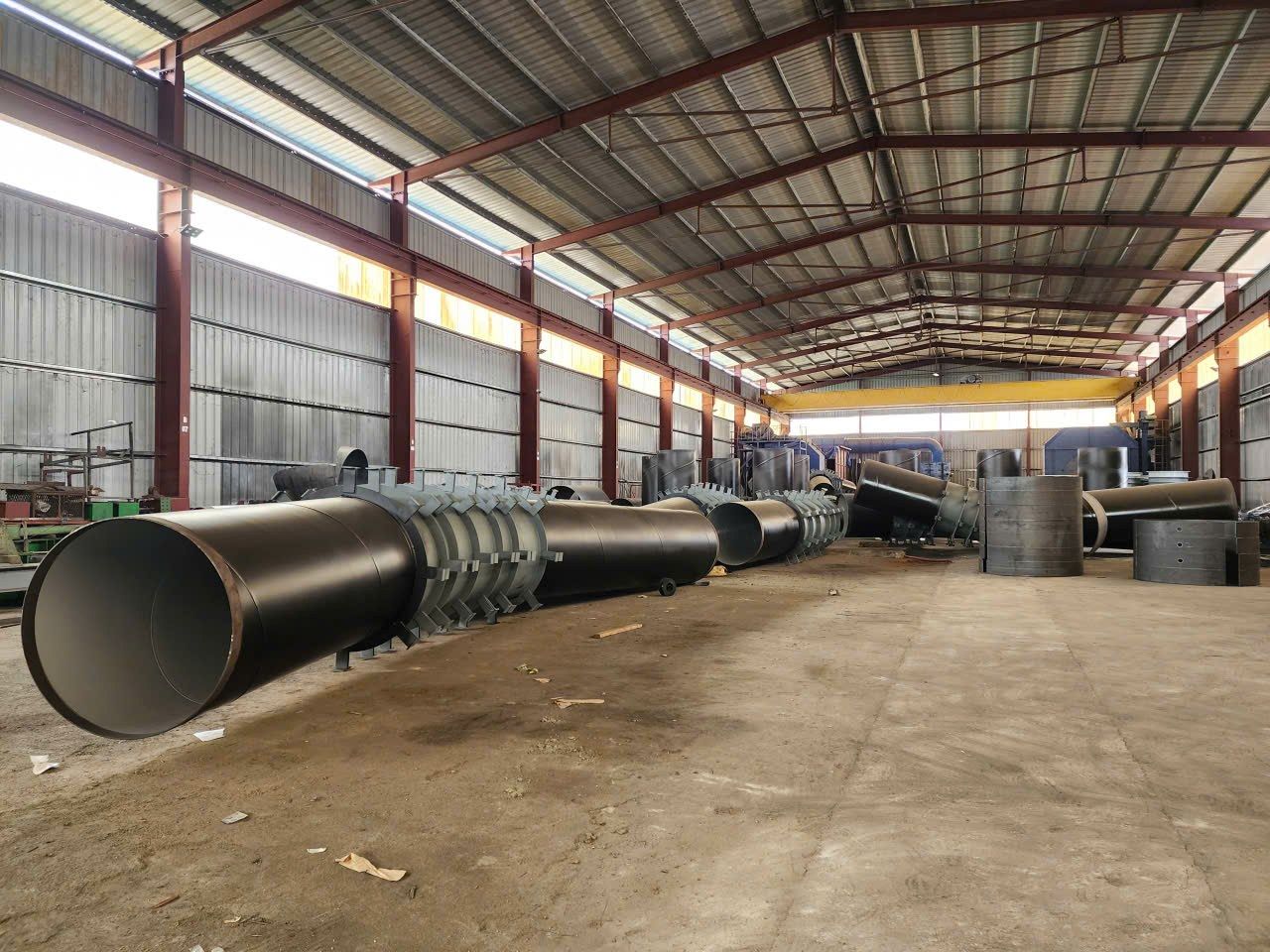 Ống thép cỡ lớn đã phủ sơn xếp dọc nhà kho công nghiệp